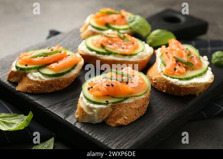 Leckere Kanapees mit Lachs, Gurke und Frischkäse auf grauem Tisch, Nahaufnahme Stockfoto