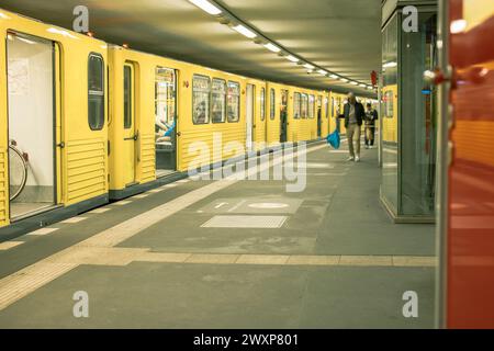 Im Inneren der U-Bahn-Station Potzdamer platz. Die gelbe U-Bahn steht auf dem Bahnsteig, ein cooles Vintage-Feeling. Einige Menschen, die unscharf sind, gehen auf sie zu Stockfoto