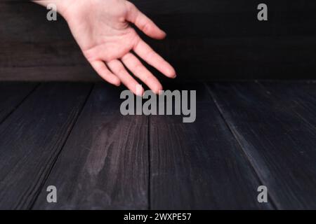 Frau, die Hand über schwarzem Holztisch hält, selektiver Fokus. Leerzeichen für Text Stockfoto