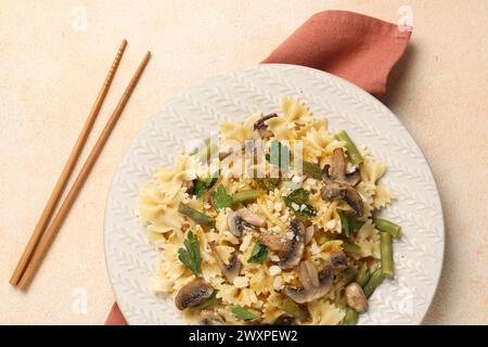 Vegetarische Pasta mit Pilzen, Petersilie, Bohnen und Käse auf orangefarbenem Tisch, Blick von oben Stockfoto
