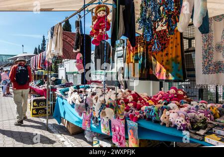 Ein Markt im Freien bietet eine Vielzahl von Artikeln zum Verkauf, darunter bunte Kuscheltiere, Puppen und Kleidung in Quarteira, Portugal. Stockfoto