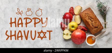 Begrüßungsbanner für Shavuot mit traditionellem Brot, Honig, Granatapfel und Äpfeln Stockfoto