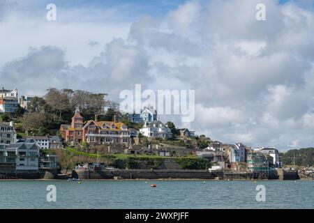 Blick auf den Salcombe Yacht Club und die umliegende Stadt, von East Portlemouth an einem Frühlingstag mit blauem Himmel und großen Wolken mit ruhigem Wasser Stockfoto