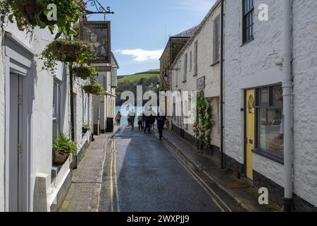 Blick entlang der Union Street in Richtung RNLI-Station und Hafen mit East Portlemouth, sichtbar an diesem sonnigen Frühlingstag, mit Menschen, die vorbeilaufen. Stockfoto