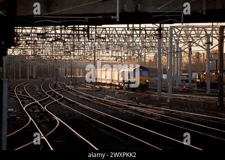 DB Schenker Baureihe 66 Diesellokomotive 66127 auf der Westküstenhauptstrecke mit einem Güterzug von Autotransportern bei Sonnenaufgang Stockfoto