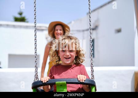 Kind, das Spaß mit seiner Mutter auf der Schaukel hat Stockfoto