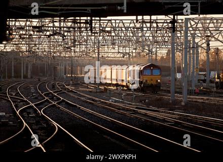 DB Schenker Baureihe 66 Diesellokomotive 66127 auf der Westküstenhauptstrecke mit einem Güterzug von Autotransportern bei Sonnenaufgang Stockfoto