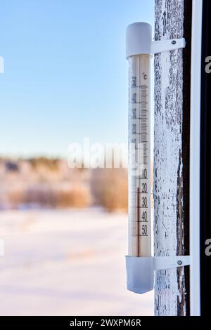 16 Grad unter Null Celsius bei einem Außenthermometer, das auf einem Holzfensterrahmen montiert ist. Stockfoto