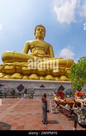 Touristen machen Fotos vor der großen und goldenen Buddha-Statue am Wat Paknam (Pak Nam) Phasi Charoen Tempel in Bangkok, Thailand an einem sonnigen Tag Stockfoto