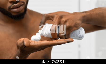 Auftragen von Rasierschaum auf die Hand im Badezimmer Stockfoto