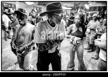 Shelby, New Jersey, USA. August 2023. SHELBY, NORTH CAROLINA: Ein Cowboy hält sich an seinem Glas Mondschein während eines Meetings and Greet in the 'BOOM-BOOM Room' während der Eröffnungsnacht des Ebony Horseman Trail Ride. Mindestens ein 800 Reiter nehmen an dem Trail Ride Teil und über 20-25.000 Zuschauer besuchten die Reiter, rodeo, Line Dance, Unterstützungsverkäufer. Die Beamten sagten. Die Veranstaltungsfläche ist 20 Hektar groß und bietet Platz für bis zu fünftausend Wohnmobile, Autos und Zelte. Den Teilnehmern wird eine Eintrittsgebühr ab 60 Dollar für die viertägige Veranstaltung berechnet, aber die Reiter sind kostenlos. Die Veranstaltung hat Platz für ein Aren Stockfoto