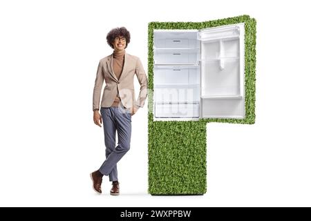 Junger Mann lehnt sich auf einen grünen umweltfreundlichen Kühlschrank isoliert auf weißem Hintergrund Stockfoto