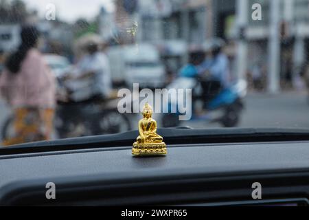 Buddha-Figur auf der Motorhaube eines Autos. Tuk Tuk-Fahrer in sri lanka. Kleine goldene Buddha-Figur vor dem Hintergrund des Fensters Stockfoto