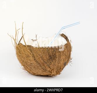 Nahaufnahme einer halben Kokosnuss mit einem Schlauch in der Mitte. Ein Glas aus Kokosnuss. Stockfoto