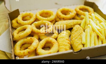 Set aus Papierkartons zum Mitnehmen mit verschiedenen Fast Food, Pommes Frites, Nuggets, Zwiebelringen und verschiedenen Saucen Stockfoto