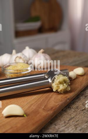 Knoblauchpresse, Zehen und Hackfleisch auf Holztisch in der Küche Stockfoto