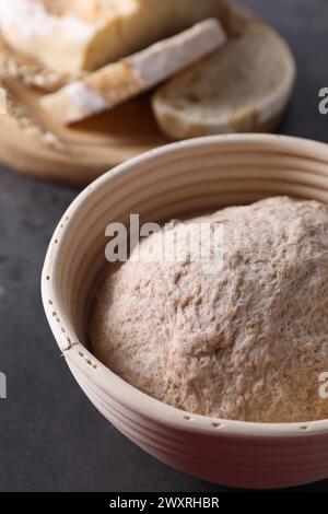 Frischer Sauerteig im Proofkorb und Brot auf grauem Tisch, Nahaufnahme Stockfoto