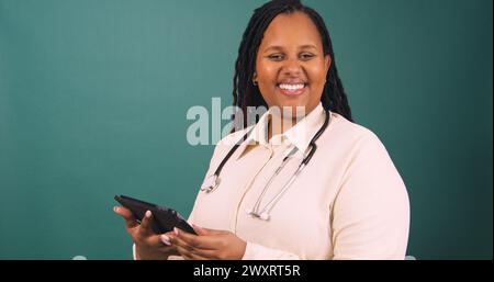 Die junge schwarze Ärztin arbeitet auf einem Tablet, lächelt in die Kamera Stockfoto