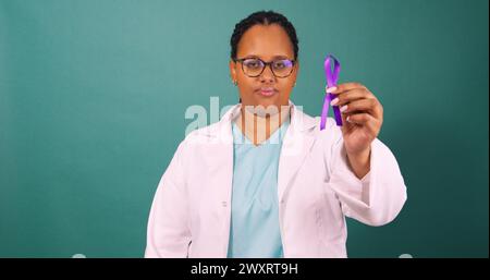 Schwarze Ärztin, die ein violettes Wahrnehmungsband hält, ernst mit weißem Fell Stockfoto