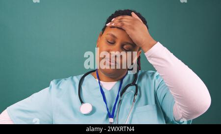 Müde junge schwarze Doktor reibt Stirn und seufzt, Ende der Operation Stockfoto