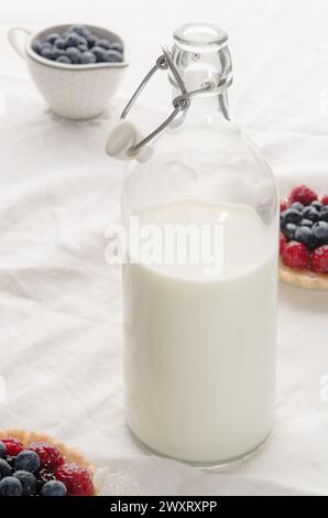 Vintage-Flasche mit Milch, Fruchtmuffins und Heidelbeeren auf einem Tisch. Stockfoto
