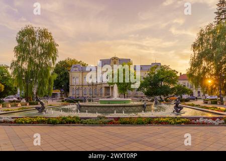 Ruse, Bulgarien - 17. September 2023: Blick bei Sonnenuntergang auf den alten Stadtplatz und das historische Museum, mit Einheimischen und Besuchern, in Russe, Northeas Stockfoto