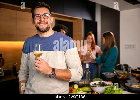 Porträt eines Mannes mit einem Glas Wein, der zu Hause mit Freunden eine Party feiert. Stockfoto