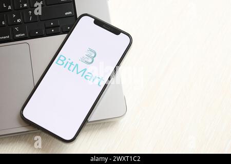 KIEW, UKRAINE - 15. MÄRZ 2024 Bitmart-Logo auf dem iPhone-Display auf dem MacBook-Panel. Portal für den Austausch von Kryptowährungen Stockfoto