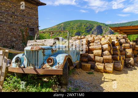 Blick auf alte Häuser, ein altes Auto und Baumstämme im Dorf Kovachevitsa, Rhodopen, Bulgarien Stockfoto