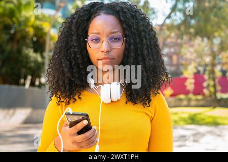Wütende junge afroamerikanische Frau, die im Internet mit intelligenter mobiler Anwendung im Freien surft. Stockfoto