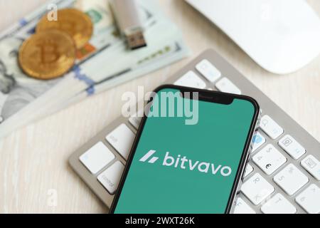 KIEW, UKRAINE - 15. MÄRZ 2024 Bitvavo-Logo auf dem iPhone-Display auf weißer Tastatur mit Geld und Bitcoins. Portal für den Austausch von Kryptowährungen Stockfoto