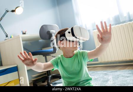 Kleiner Junge, der in seinem Zimmer Virtual-Reality-Brillen benutzt. Stockfoto