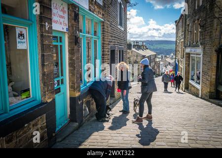 Haworth, West Yorkshire, Großbritannien. Dog Walkers halten für ein Gespräch an der Main Street. Stockfoto
