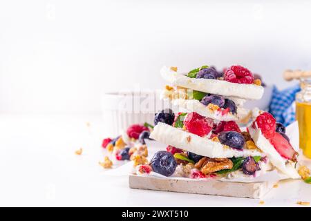 Hausgemachte gefrorene Joghurtrinde, Alternative gesunde Keto Diät Eis aus griechischem Joghurt, frische Beeren, Nüsse, Müsli, Honig, auf Backblech Deko. Stockfoto