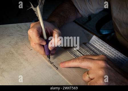 Nahaufnahme der Hände eines jüdischen Schreibers, der eine Federfeder hält und die Worte des Shema Jisrael-Gebets auf Pergament schreibt, das Encas sein wird Stockfoto