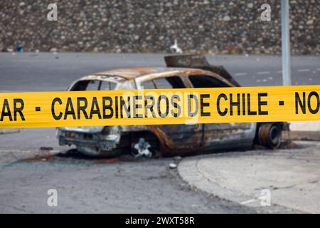 Auto verbrannt von einem Pyromanen mit einem Polizeiband, in dem auf Spanisch "Carabineros de Chile - No Pasar" geschrieben ist. Stockfoto