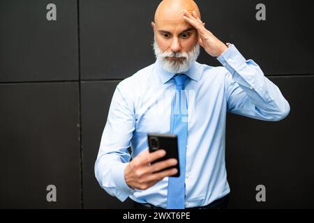 Porträt eines verärgerten leitenden Managers mit seinem Smartphone Stockfoto