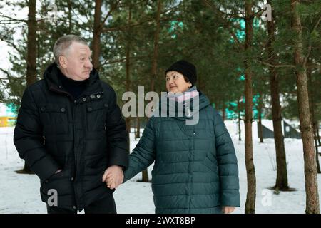 Niedliches, reifes Paar, das im Winter beim Spaziergang im Park Liebe für einander erlebt Stockfoto