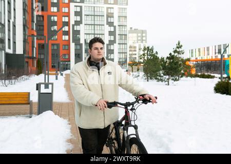 Ein junger Europäer, der in einer Winterjacke gekleidet ist, fährt mit dem Fahrrad Stockfoto