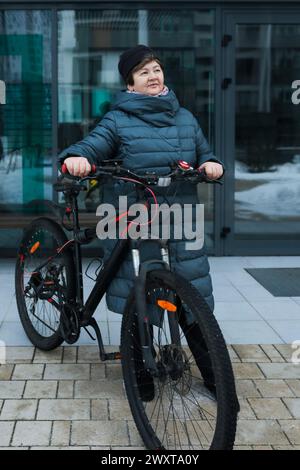 Reife Europäerin geht im Winter mit dem Fahrrad spazieren Stockfoto