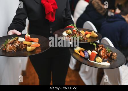 Der Kellner serviert Speisen, Fleisch und Gemüse im Restaurant Stockfoto