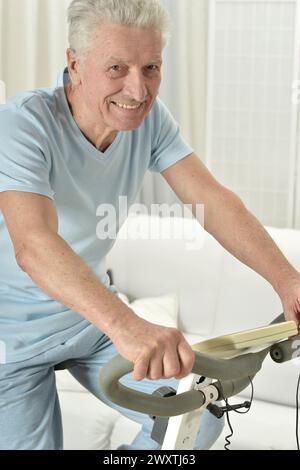 Ein älterer Mann trainiert auf einem Heimtrainer Stockfoto