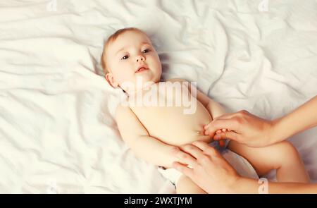 Mutter gibt Massage für Baby, das zu Hause auf dem Bett liegt, Kind und Gesundheitskonzept Stockfoto