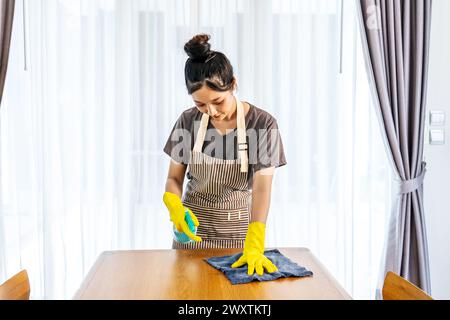 Eine Frau in gelben Handschuhen putzt gerne einen Tisch Stockfoto