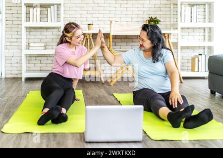 Die Tochter und ihre Mutter haben sich beim Training auf dem Boden High Five Stockfoto