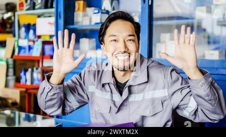 Ein junger Mann sitzt an seinem Schreibtisch vor einem Laptop und winkt begeistert mit den Händen Stockfoto