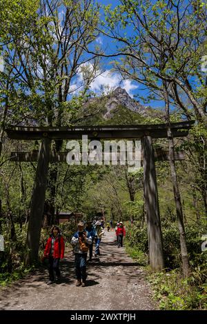 KAMIKOCHI, JAPAN - 24. MAI 2023: Wanderer, die unter dem Torii-Tor des Hotaka-Schreins in Kamikochi, Nagano, Japan passieren. Stockfoto