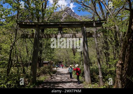 KAMIKOCHI, JAPAN - 24. MAI 2023: Wanderer, die unter dem Torii-Tor des Hotaka-Schreins in Kamikochi, Nagano, Japan passieren. Stockfoto