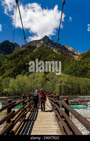 KAMIKOCHI, JAPAN - 24. MAI 2023: Wanderer überqueren die Myojin-Hängebrücke über den Azusa-Fluss in Kamikochi, Nagano, Japan Stockfoto