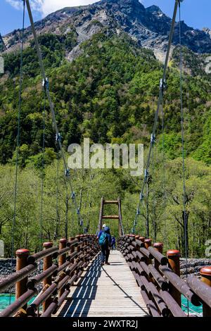 KAMIKOCHI, JAPAN - 24. MAI 2023: Wanderer überqueren die Myojin-Hängebrücke über den Azusa-Fluss in Kamikochi, Nagano, Japan Stockfoto